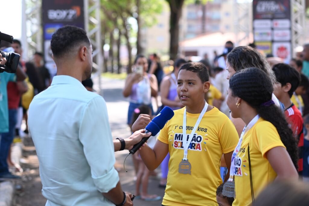 Participante da corrida com a medalha no peito dando entrevista após a prova. 