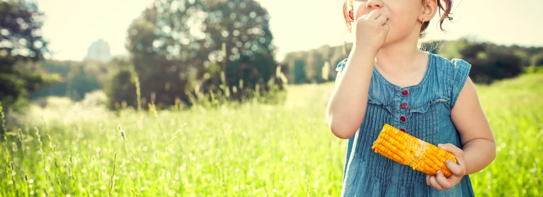 Girl eating corn in a field